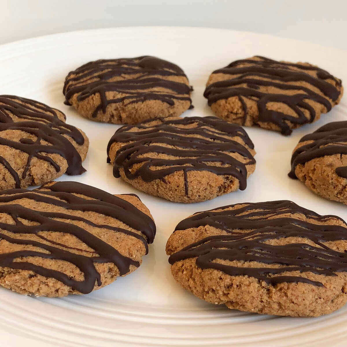 Seven cookies drizzled with chocolate.