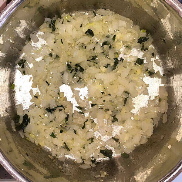 Onions and herbs cooking in a pot.