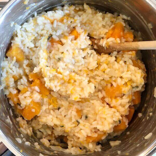 Risotto with chunks of squash in a metal pot.