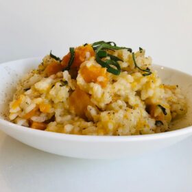 Vegan butternut squash risotto in a bowl with fresh sage sprinkled on top.
