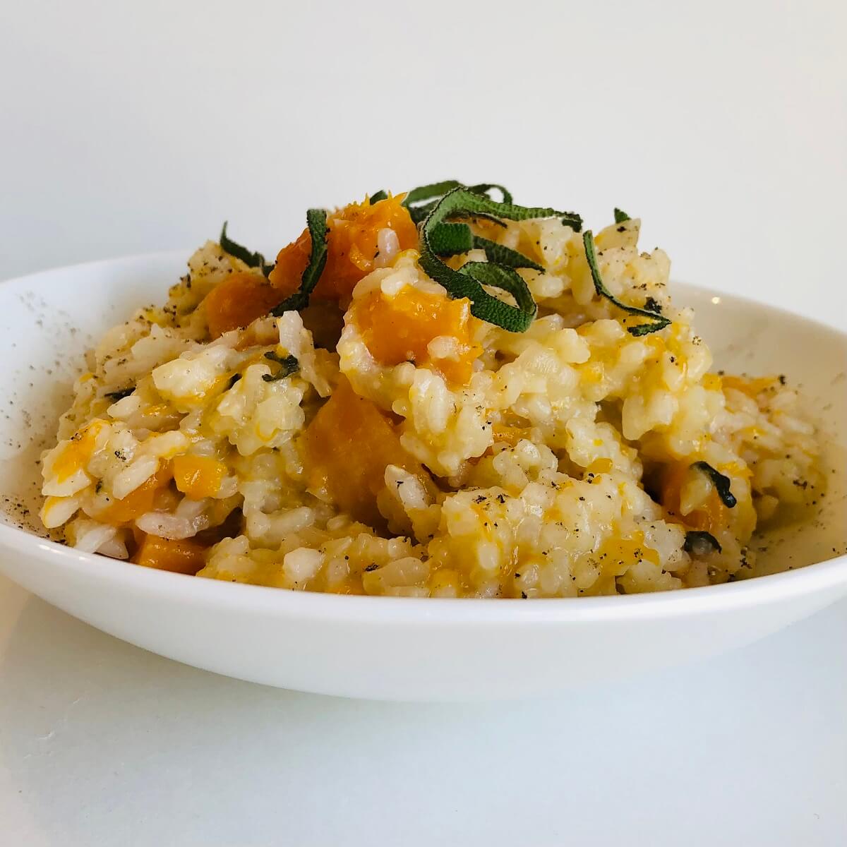 Vegan butternut squash risotto in a bowl with fresh sage sprinkled on top.