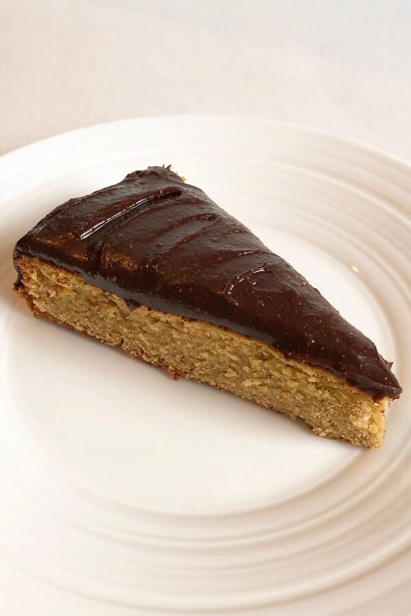 A slice of cake with a thick layer of chocolate icing.