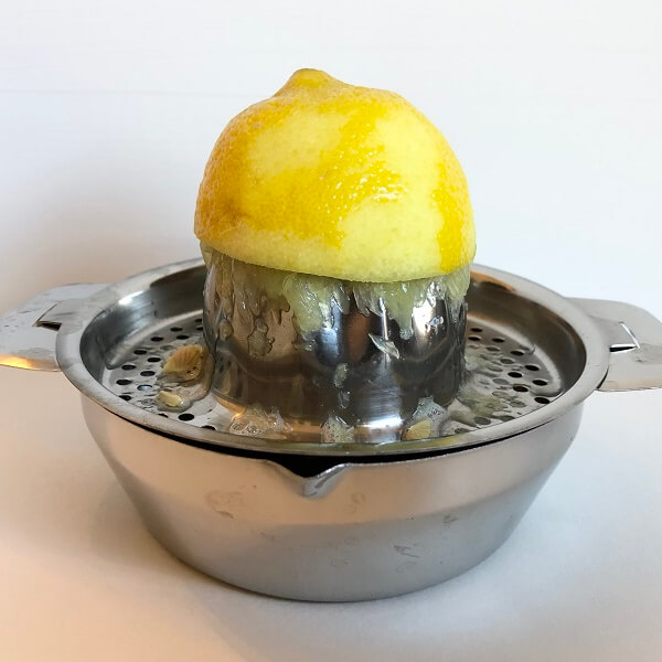 Half of a lemon on top of a metal citrus juicer.