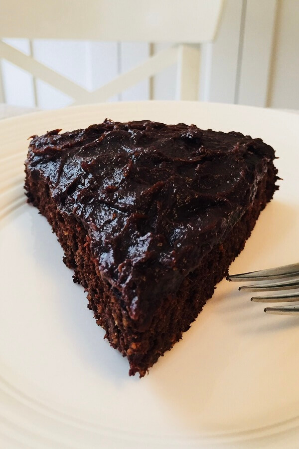 A big slice of cake with frosting on a plate.