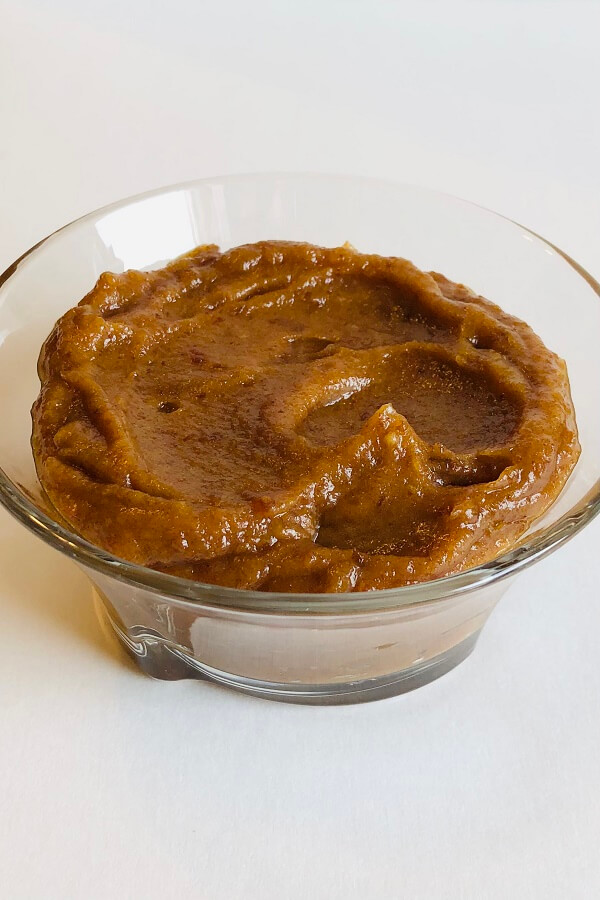 Pureed dates in a bowl against a white background.