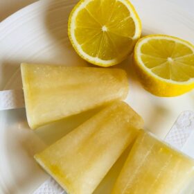 Yellow popsicles on a plate with lemons.