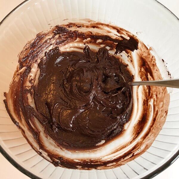 Frosting being mixed in a large glass bowl.