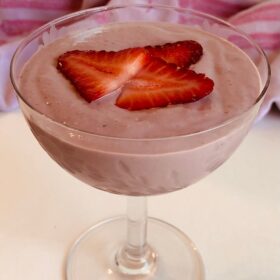 Mousse in a glass dish with strawberries on top.