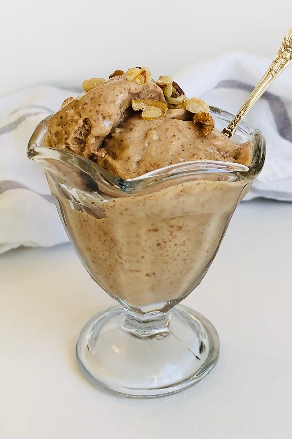 Ice cream with a spoon in a glass dish.