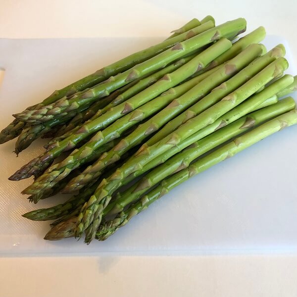 Raw asparagus spears on a cutting board.