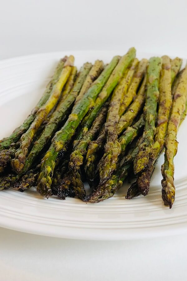 Cooked asparagus on a white plate.
