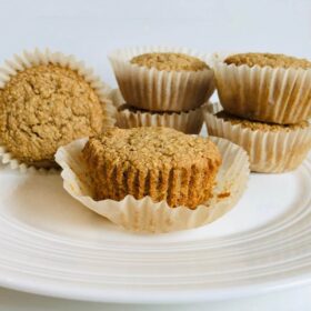 Vegan applesauce muffins in paper baking cups on a white plate.