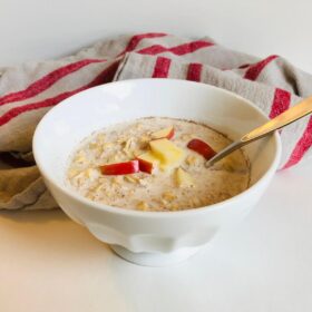 A bowl of maple cinnamon overnight oats with chopped apples on top.