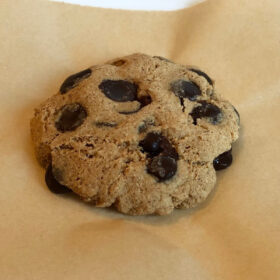 A cookie cooling on parchment paper on top of a white plate.