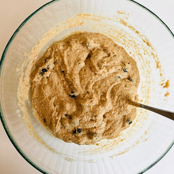 Thick muffin batter in a large bowl with a spoon.
