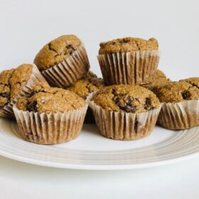 Eight gluten-free blackberry muffins on a white plate.