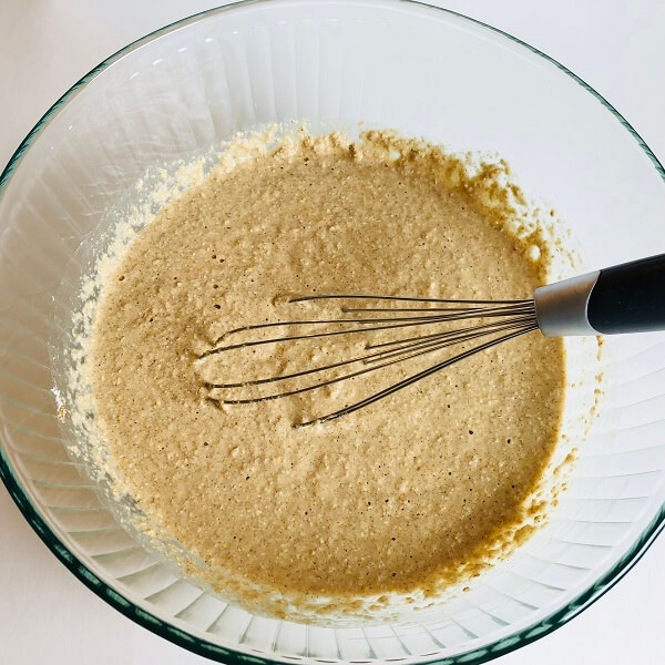 Batter in a glass mixing bowl with a whisk.