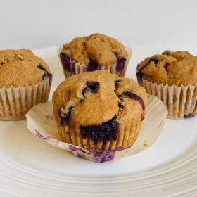 Four vegan lemon blueberry muffins on a plate.