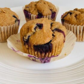 Muffins in paper baking cups with the paper peeled off one of them.