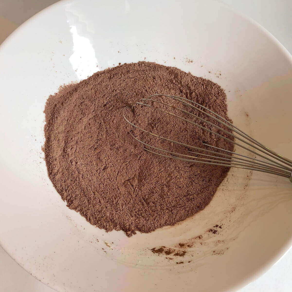 Dry ingredients in a bowl with a whisk.