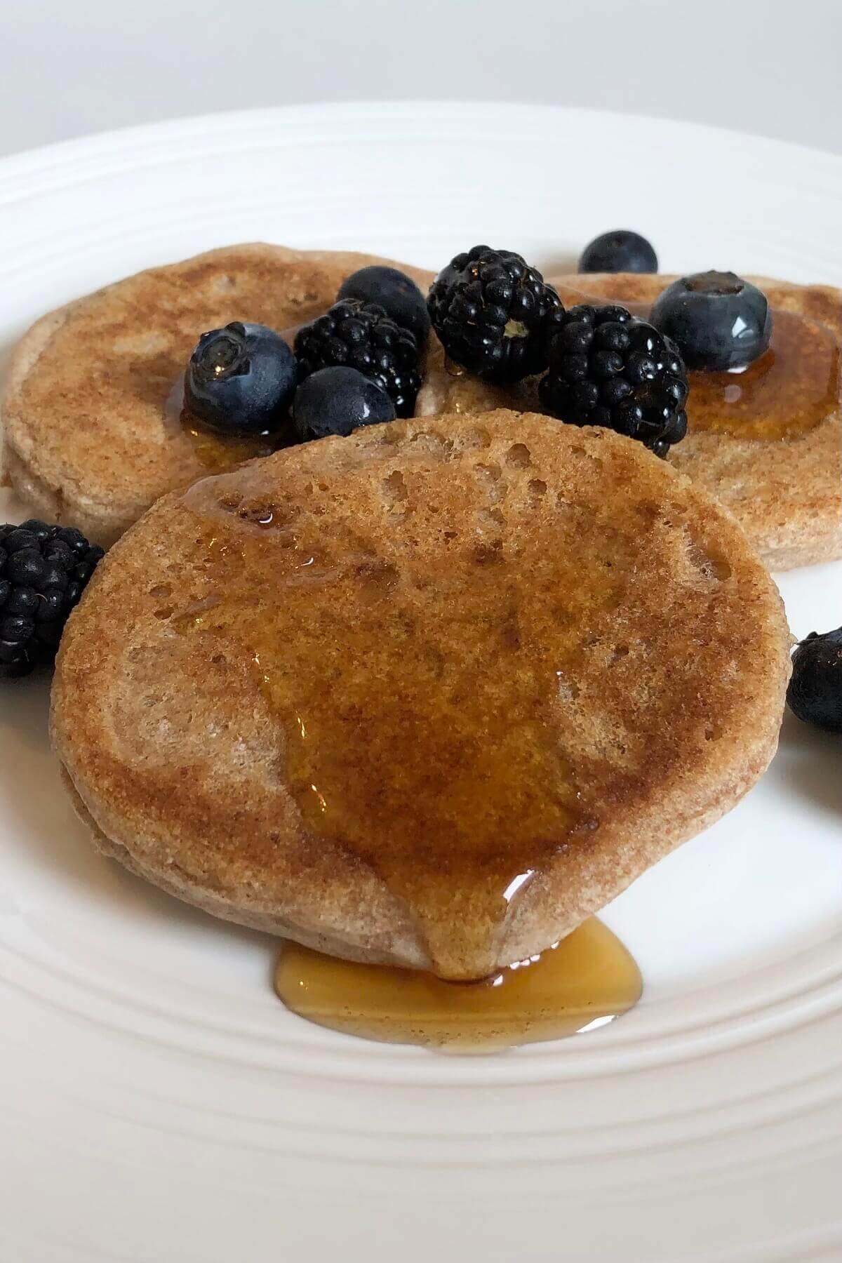 Pancakes with berries and maple syrup dripping off.