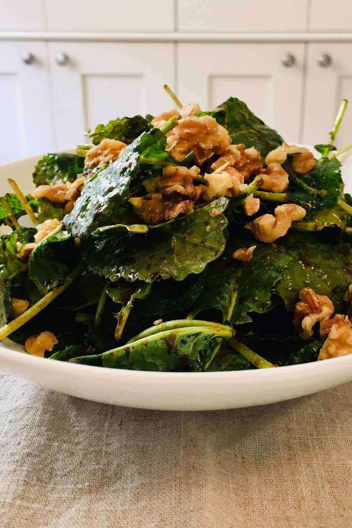 Salad tossed with dressing in a white bowl.