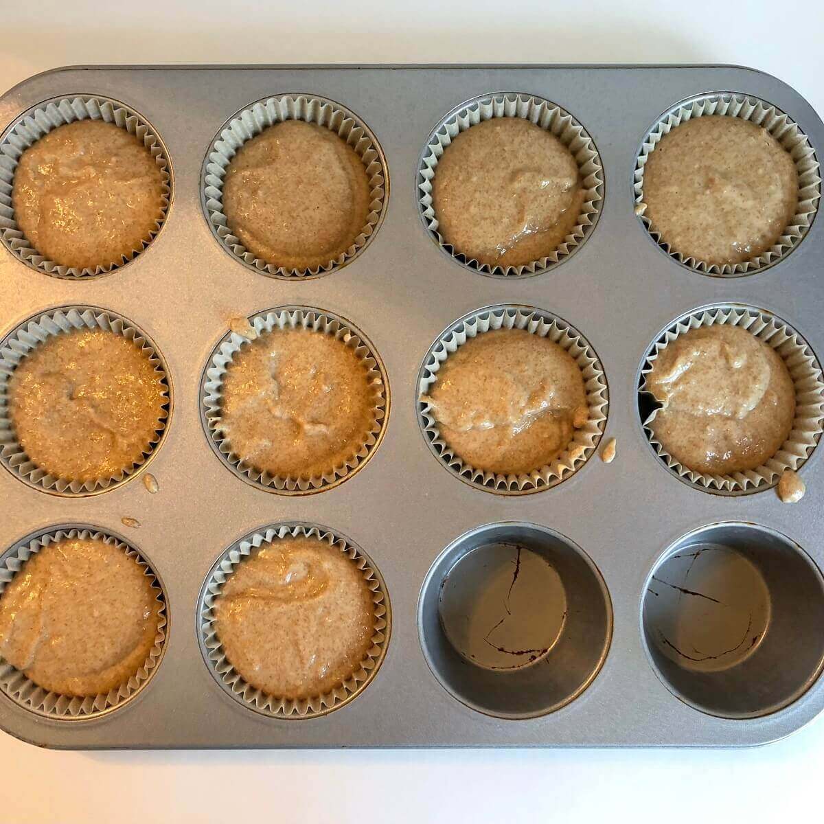 Ten raw spelt muffins in a baking pan.