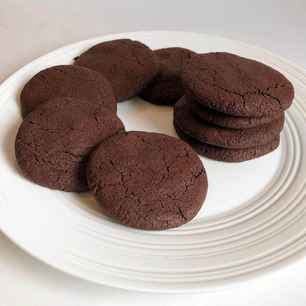 Nine chocolate cookies displayed on a white plate.