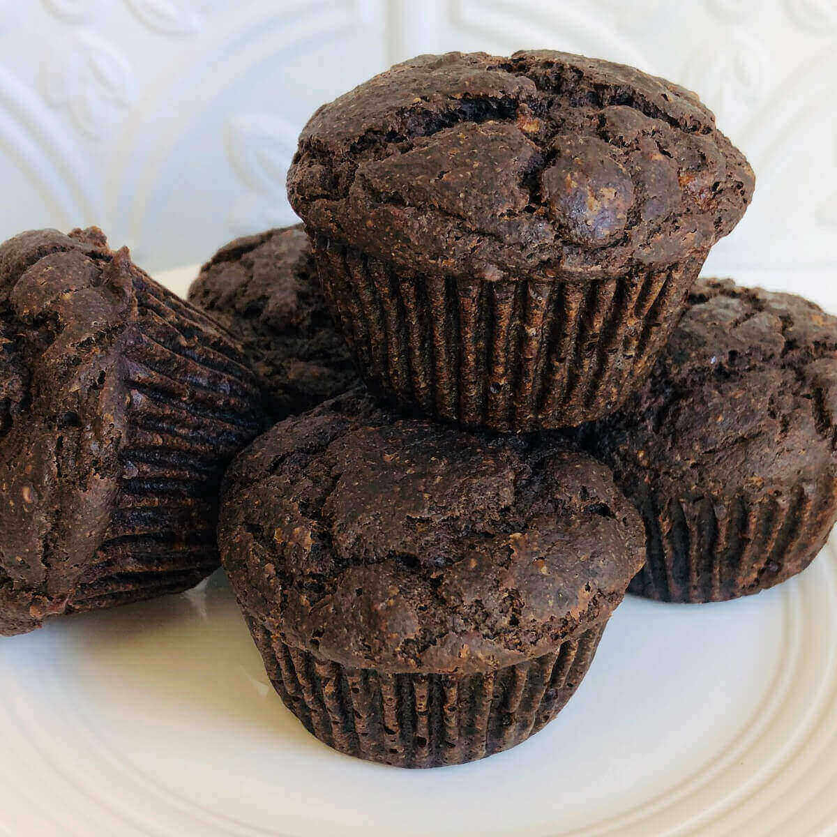 Five buckwheat muffins on a white plate.