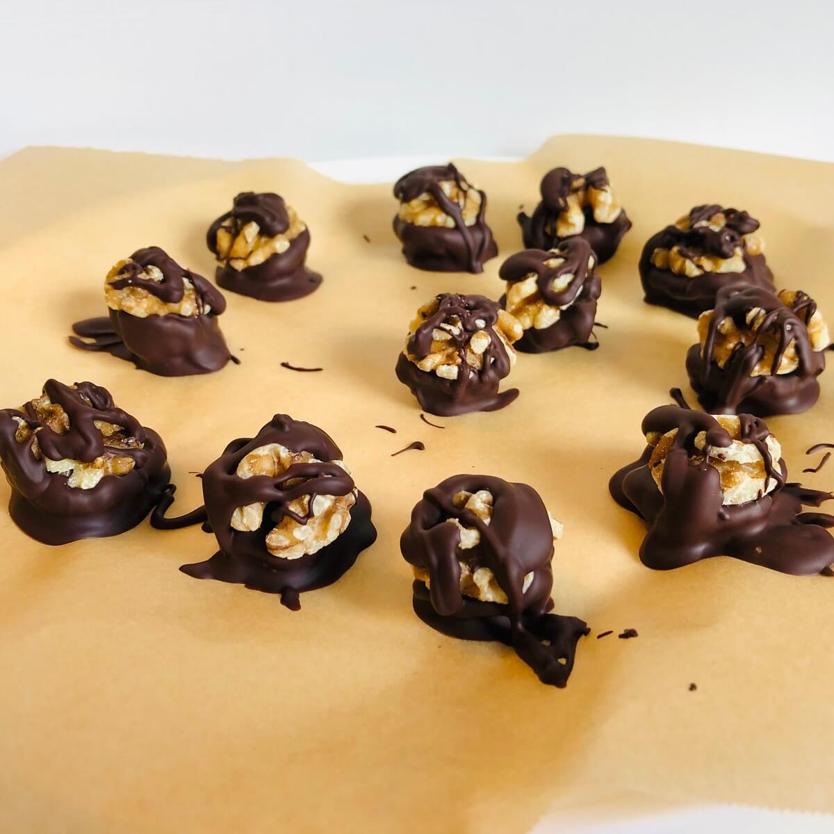 Chocolate dipped nuts on a piece of parchment paper.
