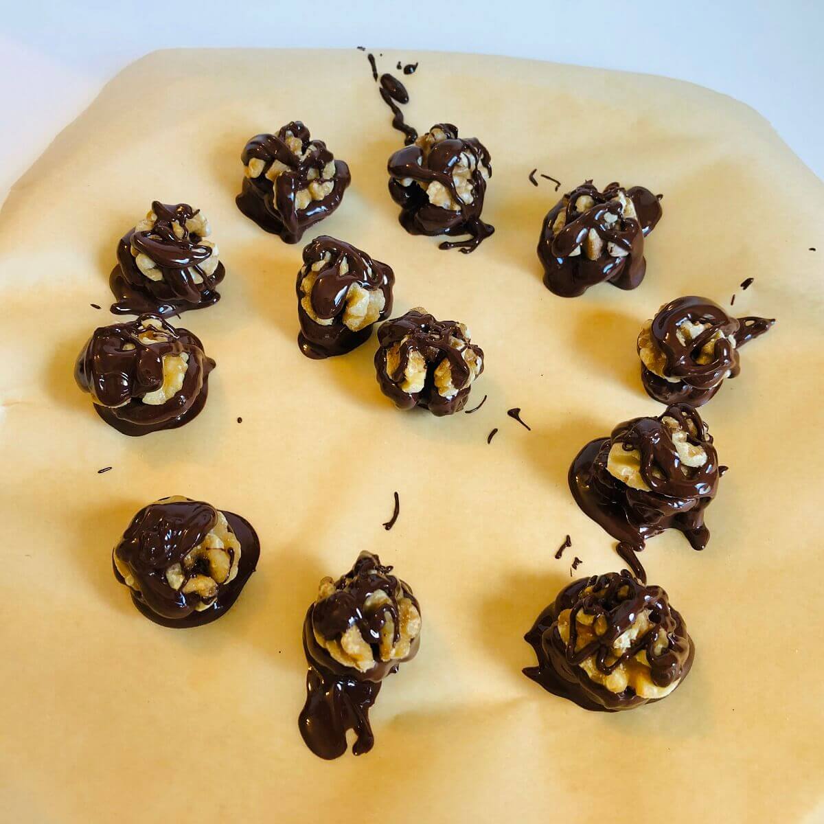 Nuts dipped in chocolate on a piece of parchment paper.