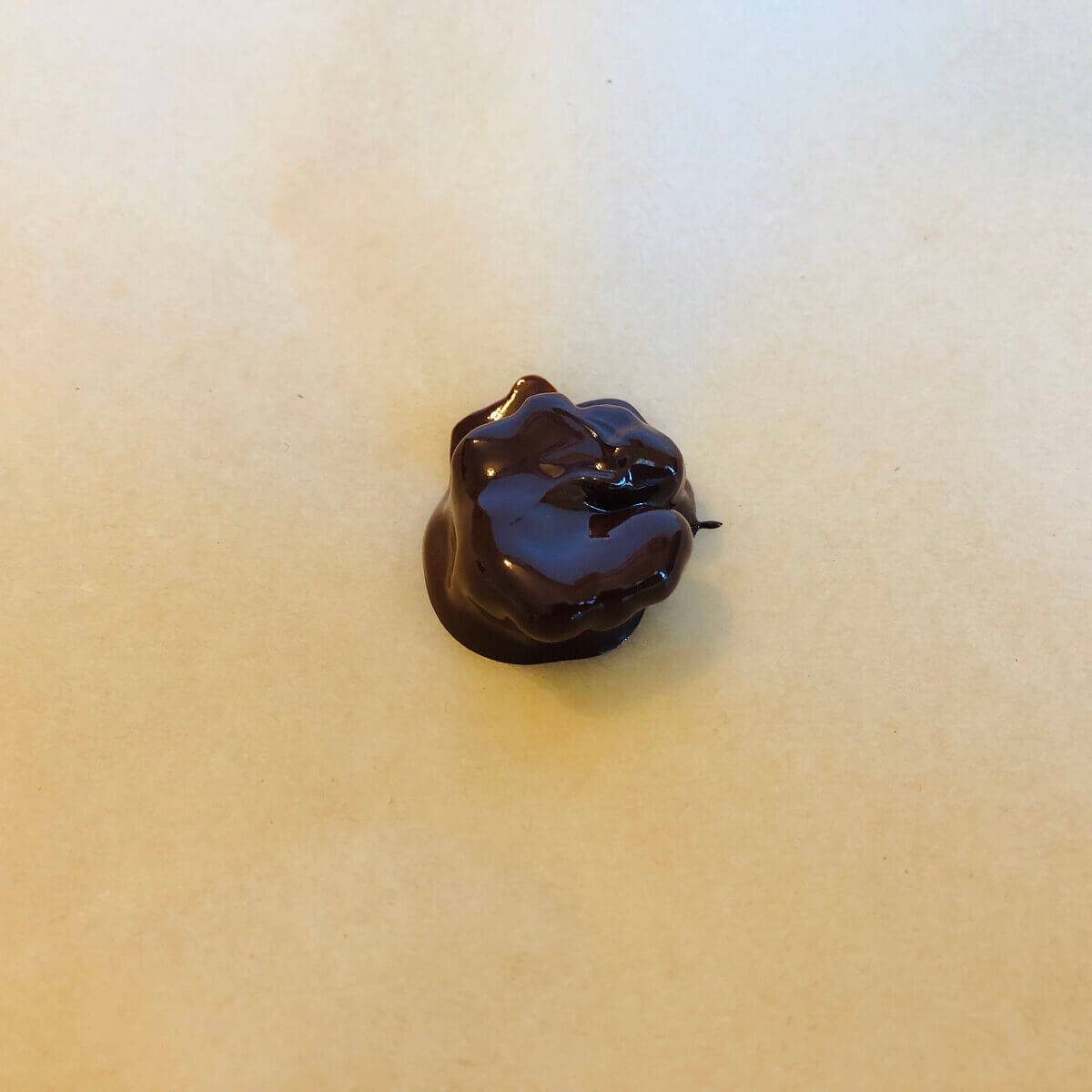 A walnut half coated in melted dark chocolate.