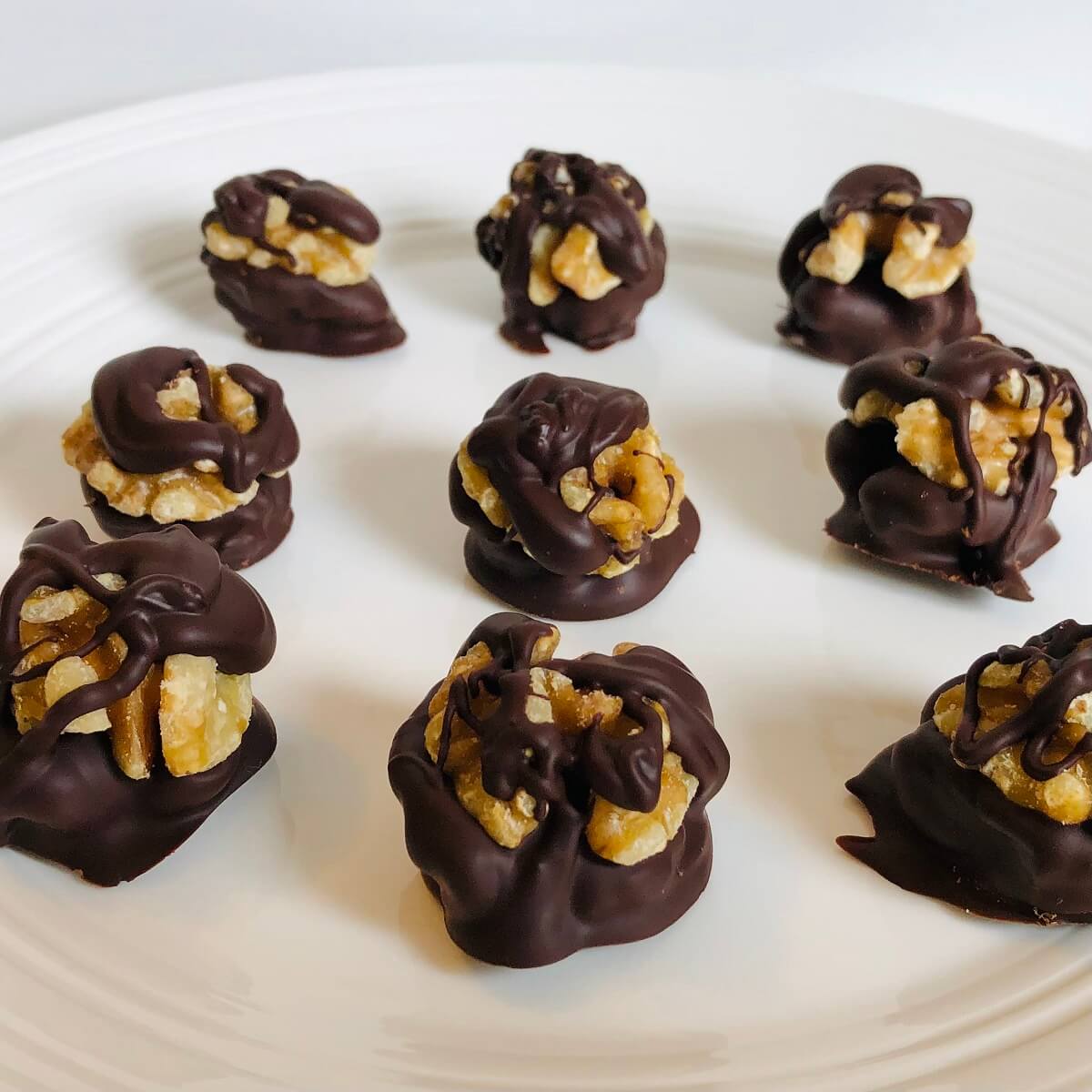Chocolate coated walnuts on a white plate.