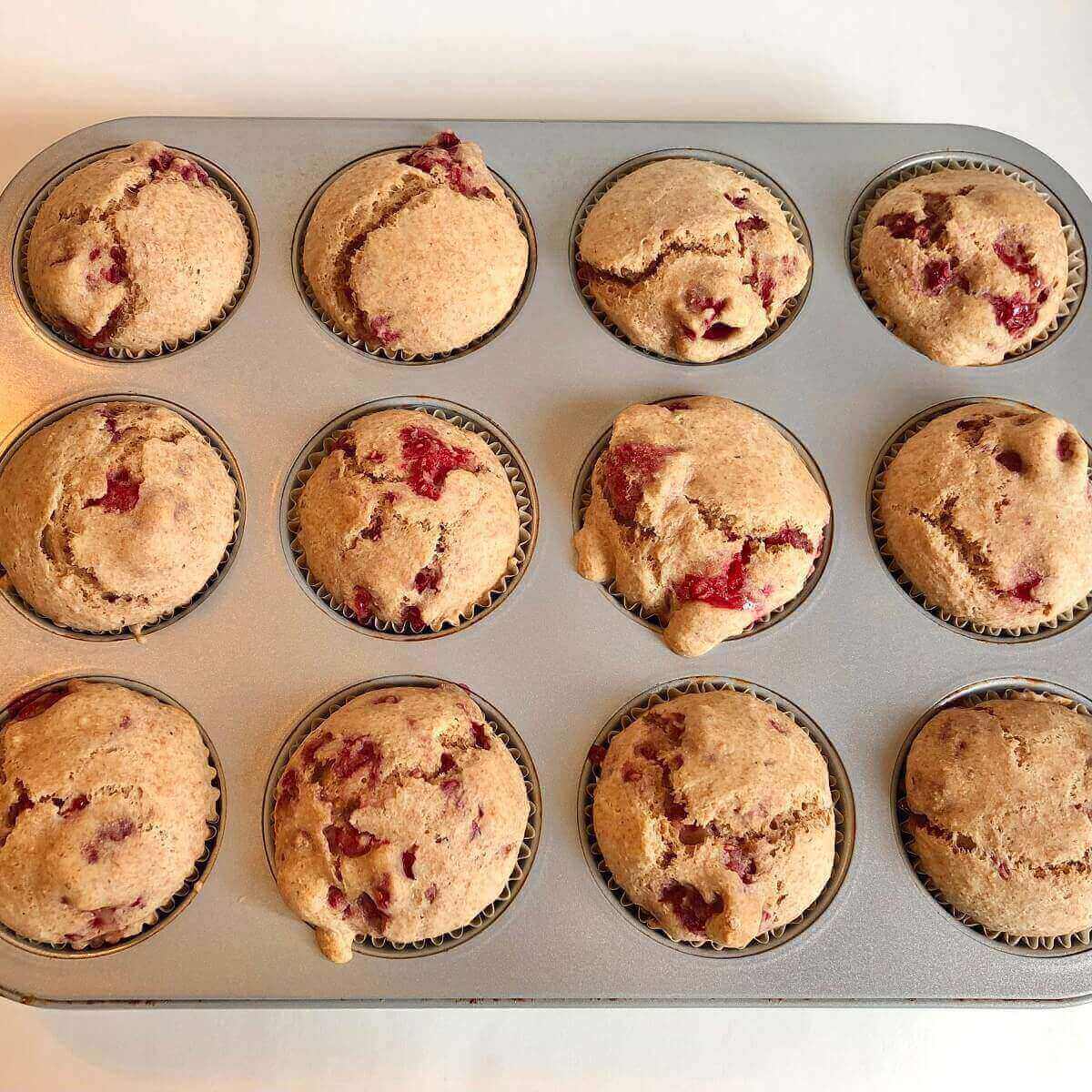 Freshly baked raspberry muffins in a metal pan.