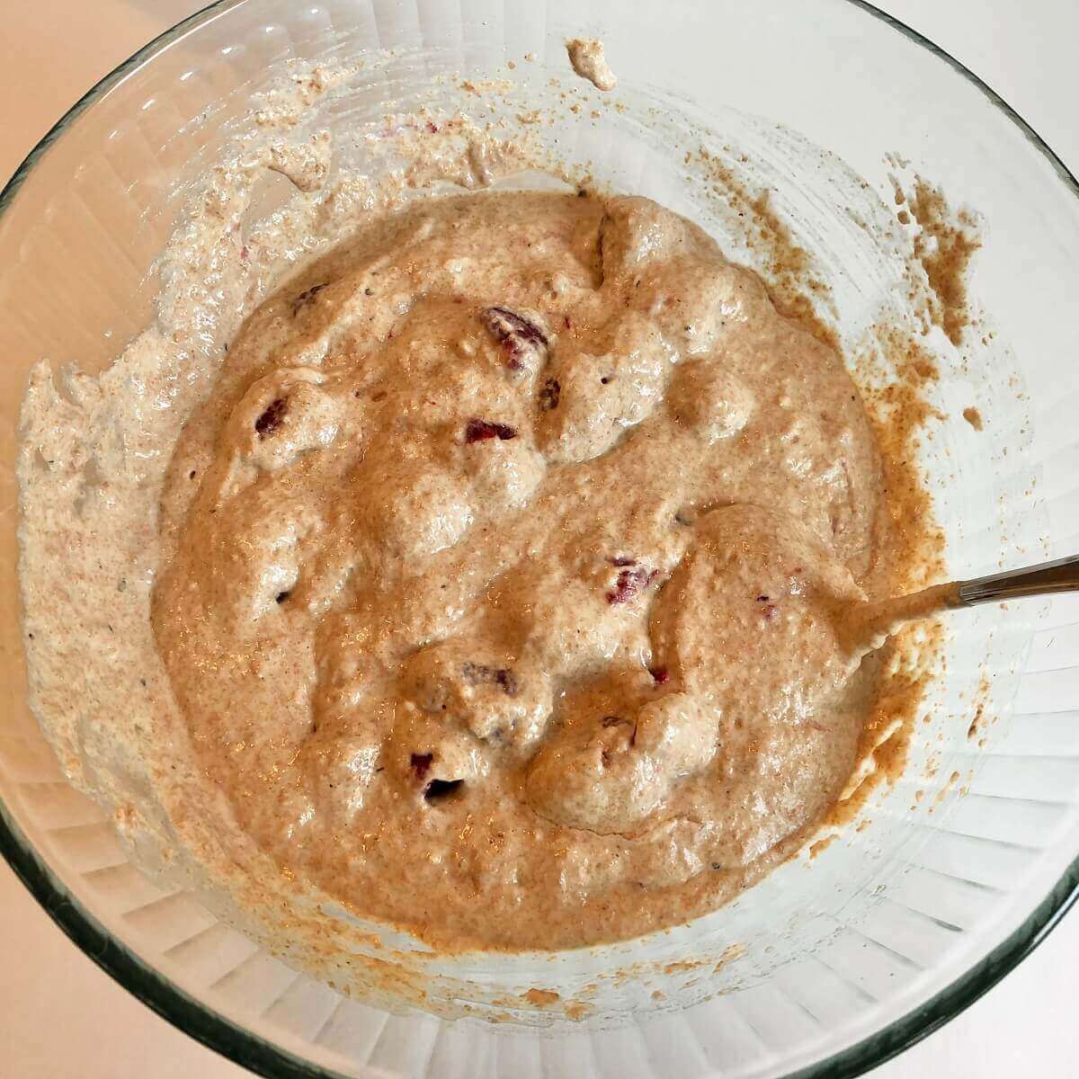 Raspberry muffin batter in a glass mixing bowl.