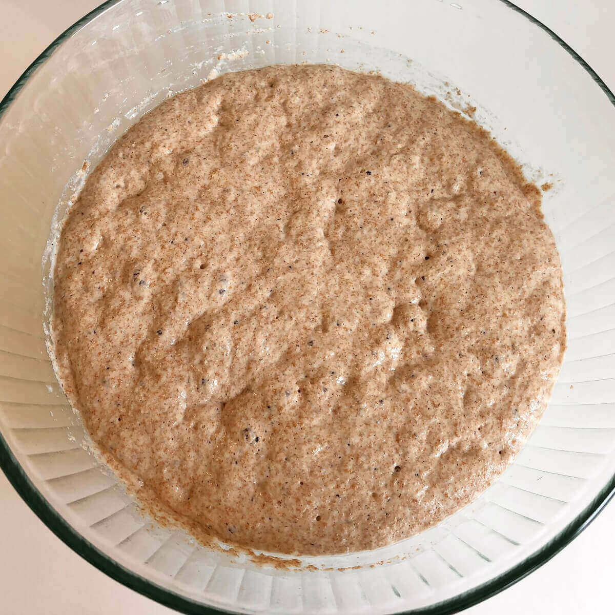 Bread dough rising in a glass bowl.