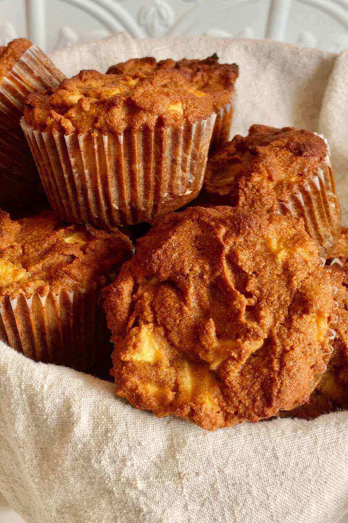 Apple muffins in a basket lined with a linen napkin.