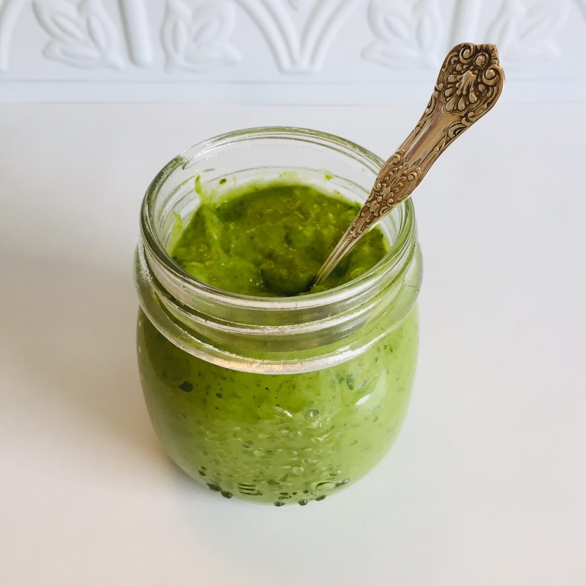 Avocado green goddess dressing in a jar with a spoon.