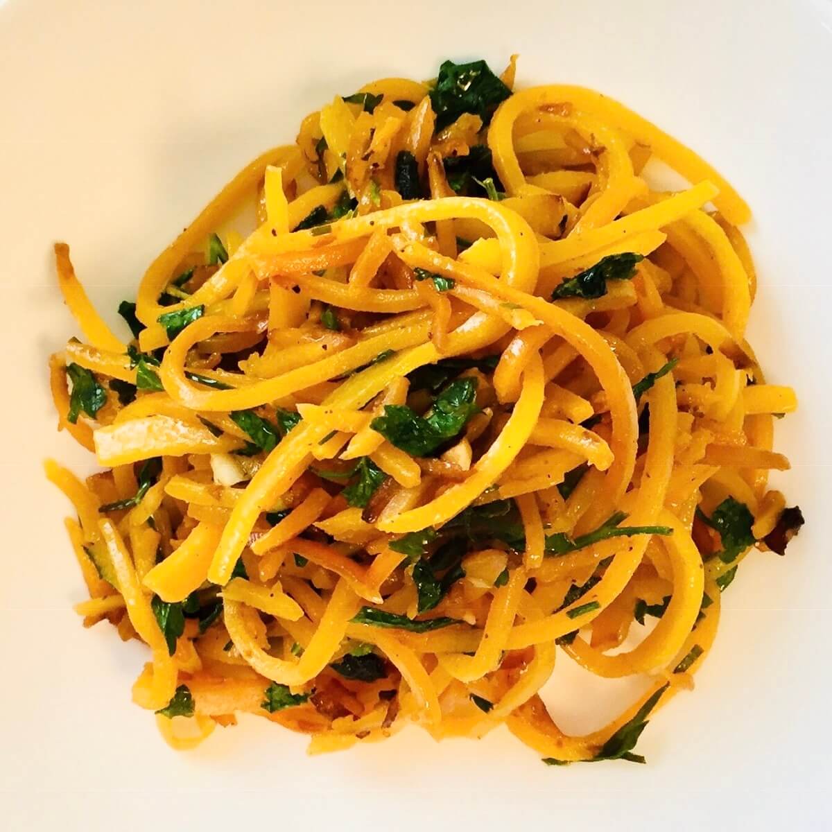 Spiralized butternut squash in a white bowl.