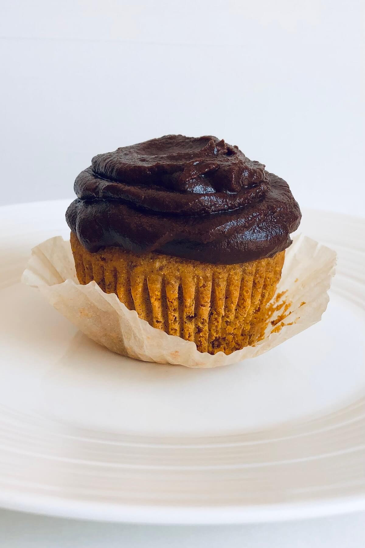 A frosted cupcake on a white plate.