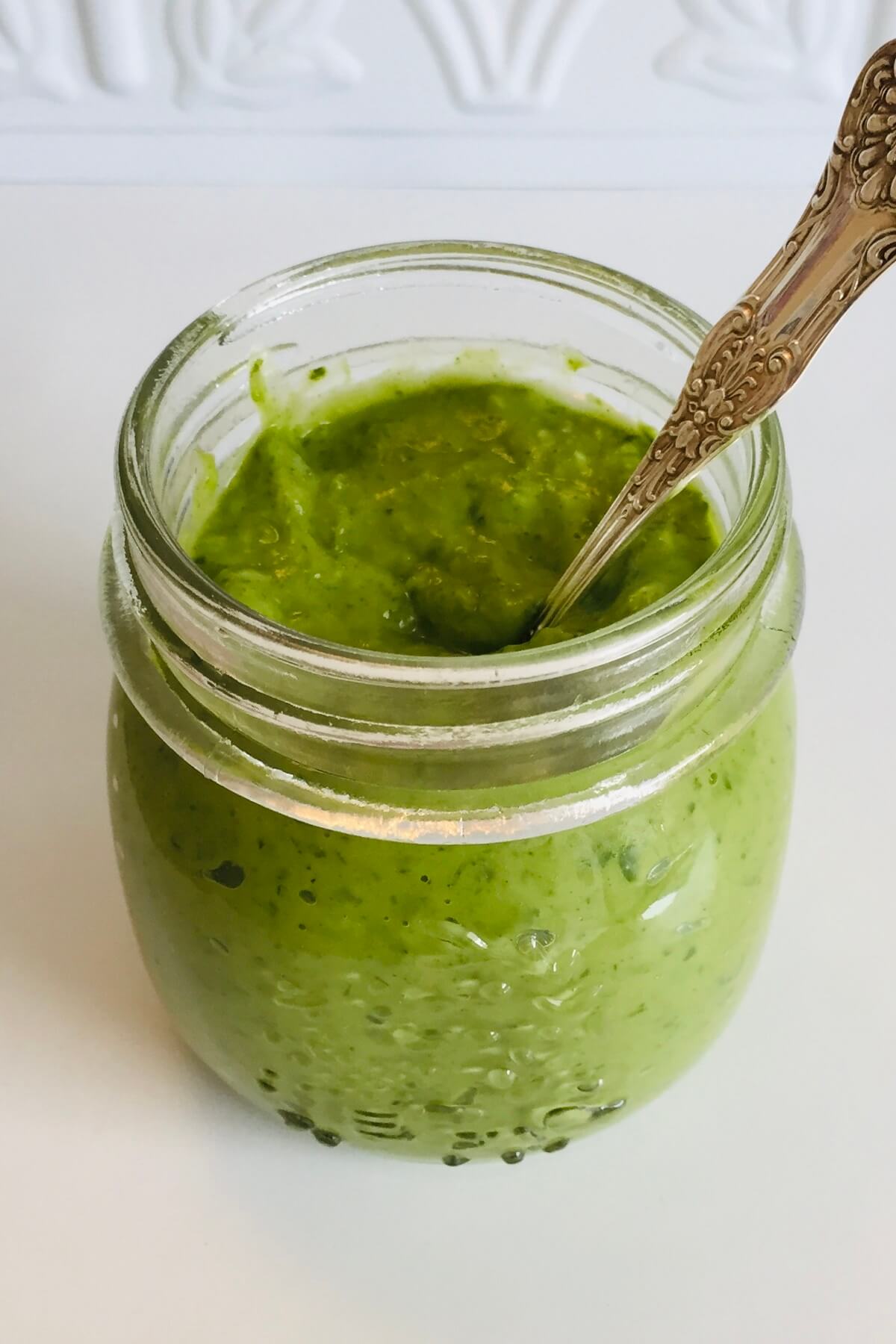 Green salad dressing in a glass jar.