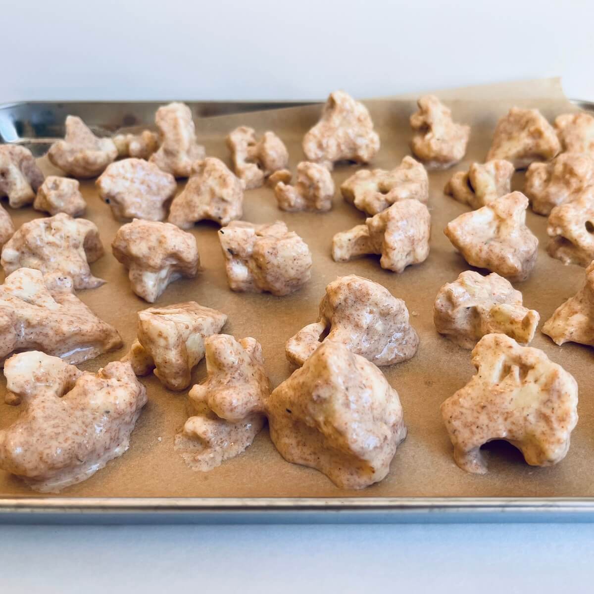 Pieces of battered cauliflower on a sheet pan.