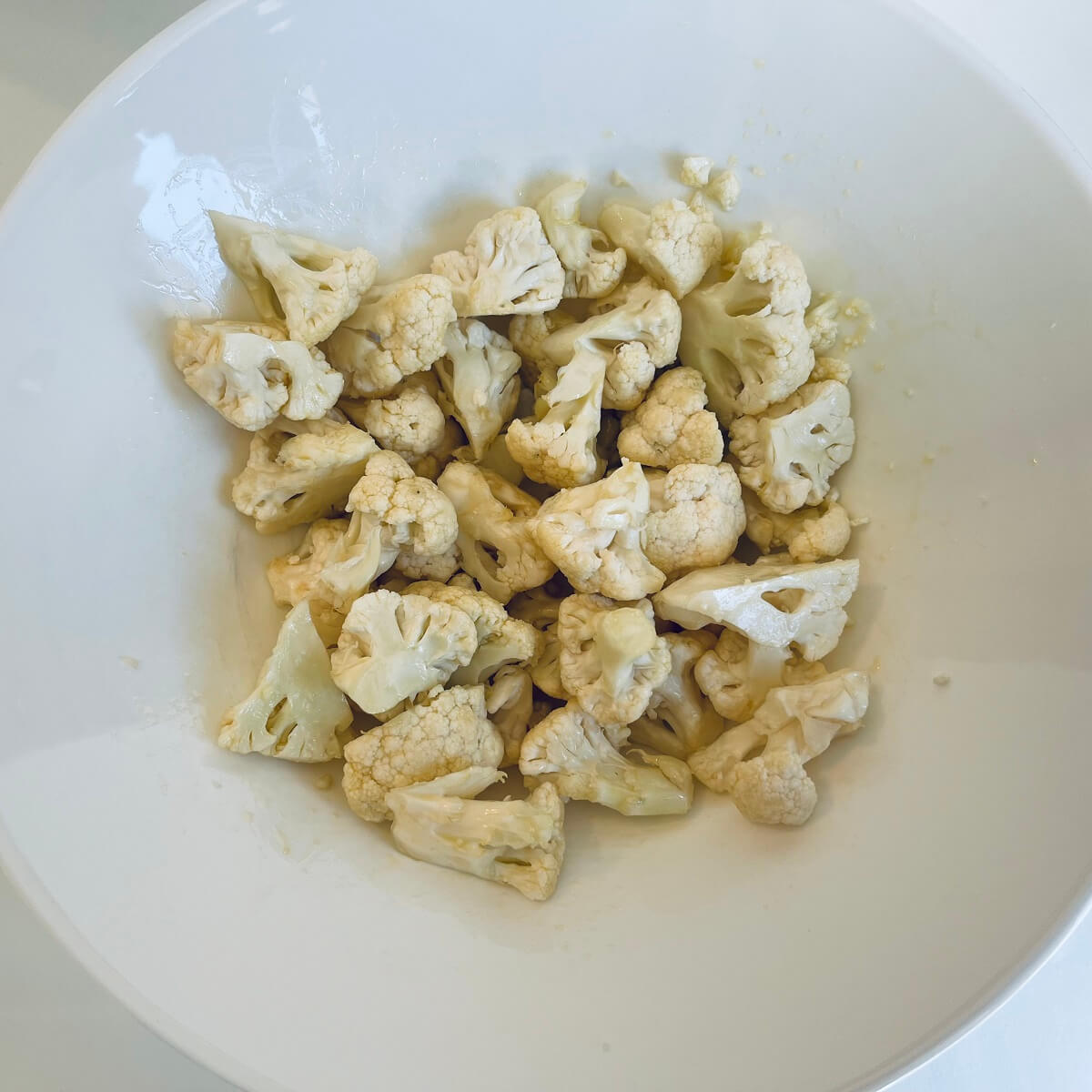 Cauliflower pieces in a large white bowl.