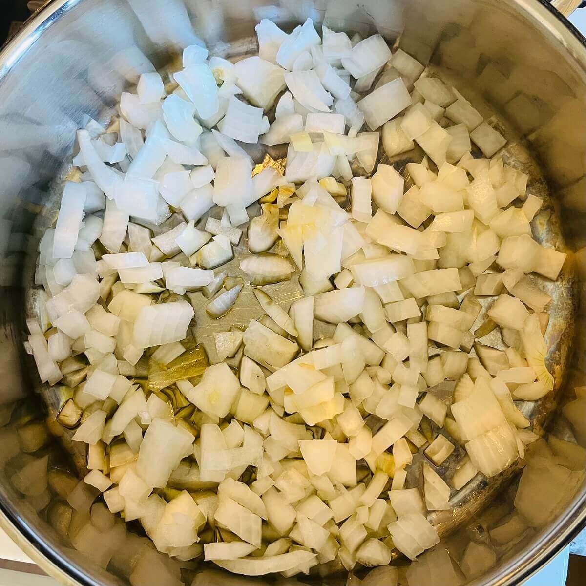 Raw chopped onions in a metal pan.