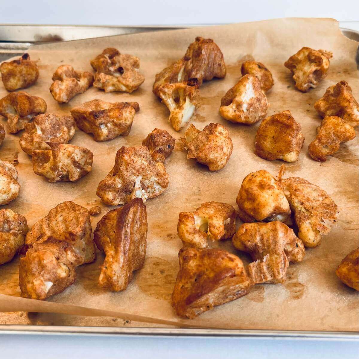 Pieces of crispy cauliflower on a baking tray.