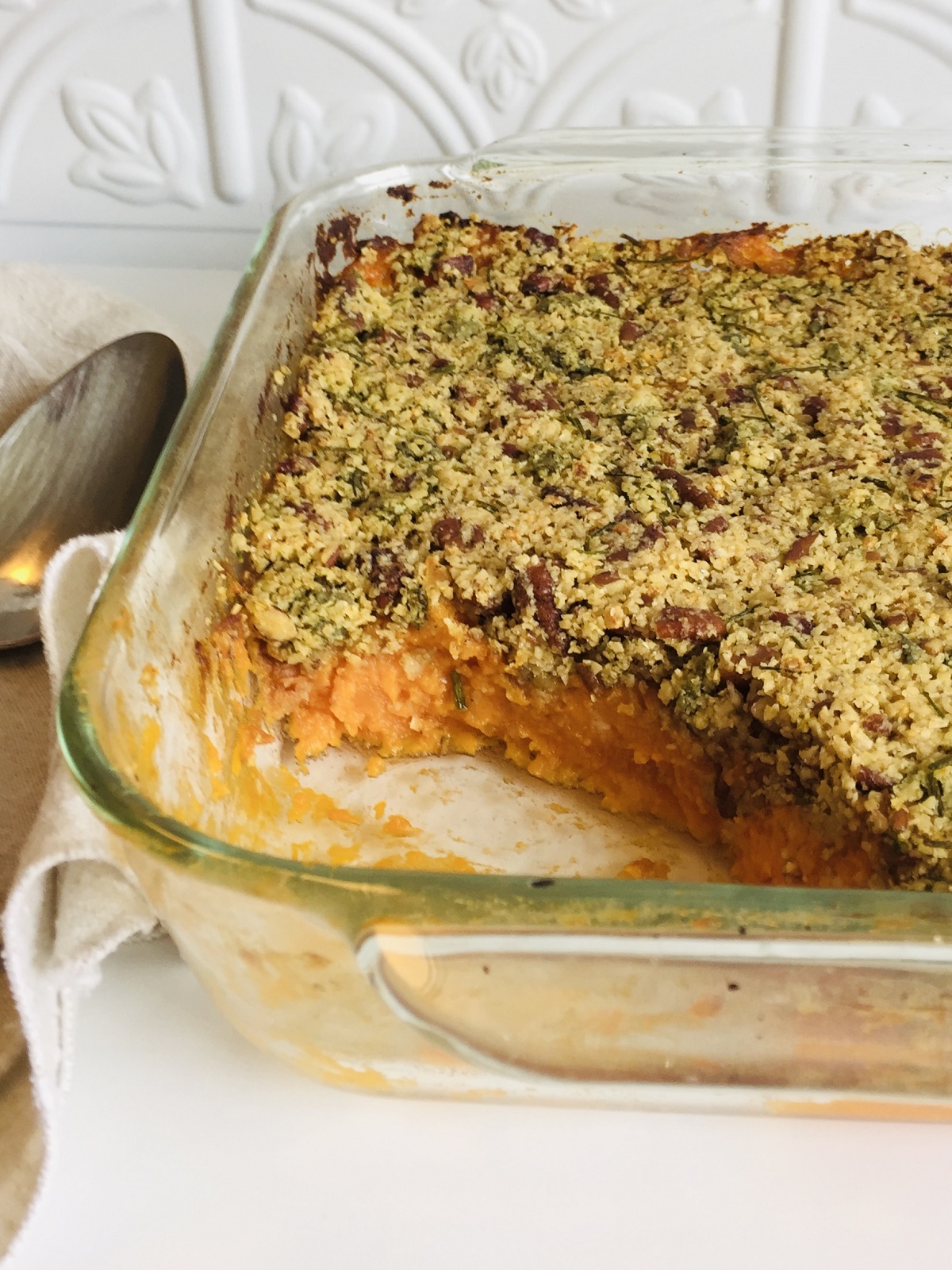 A casserole in a glass dish with a spoon next to it.