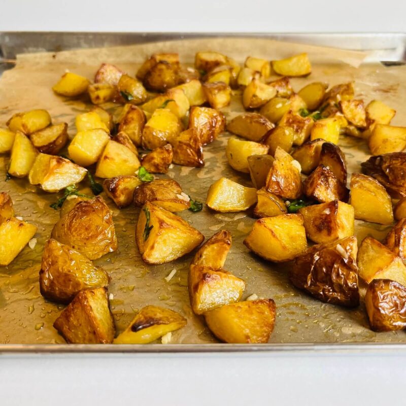 Roasted potatoes on a parchment paper lined baking sheet.
