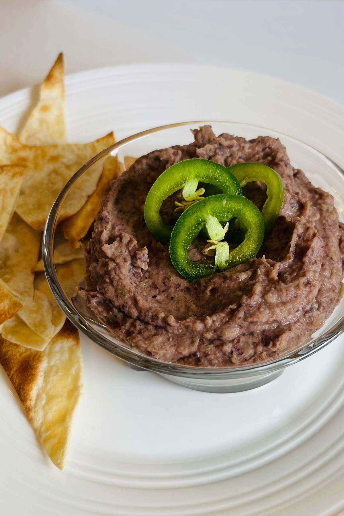 Bean dip in a bowl next to some chips.