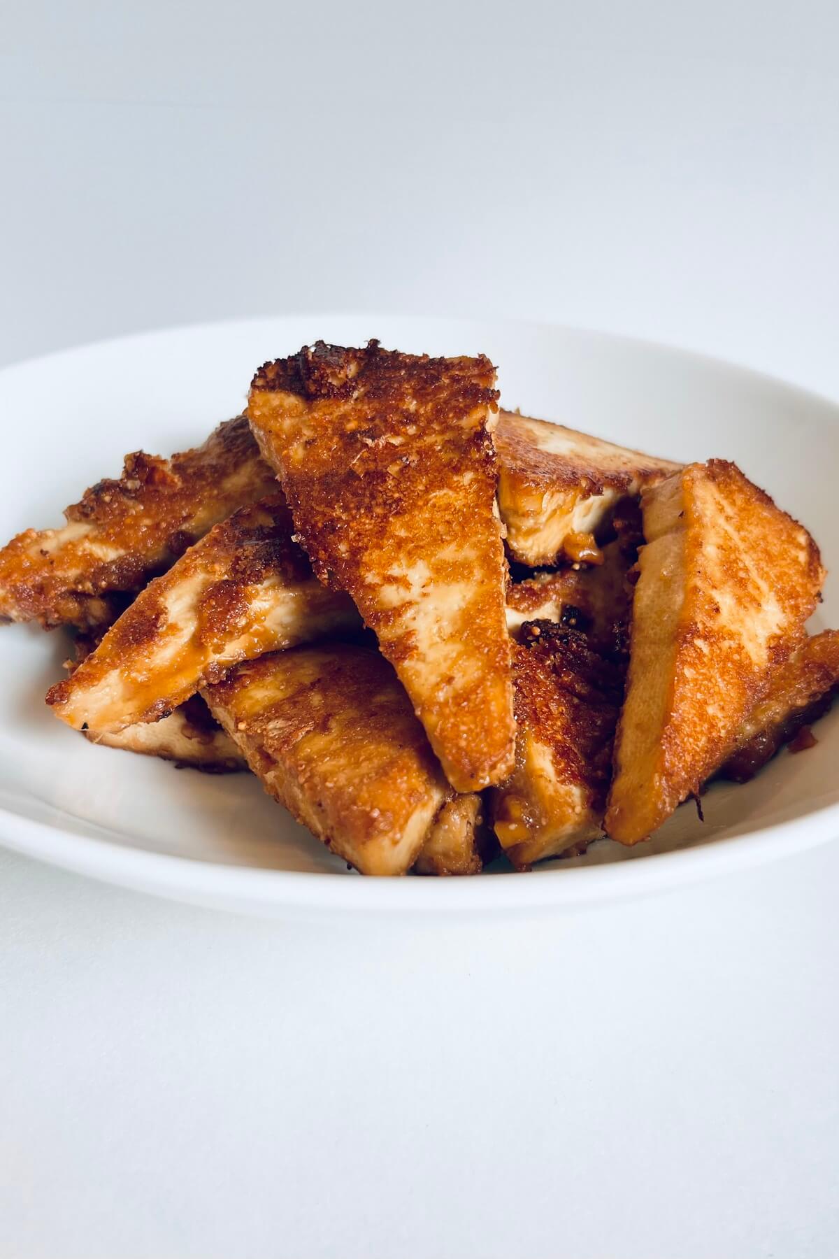 Cooked tofu pieces in a white bowl.