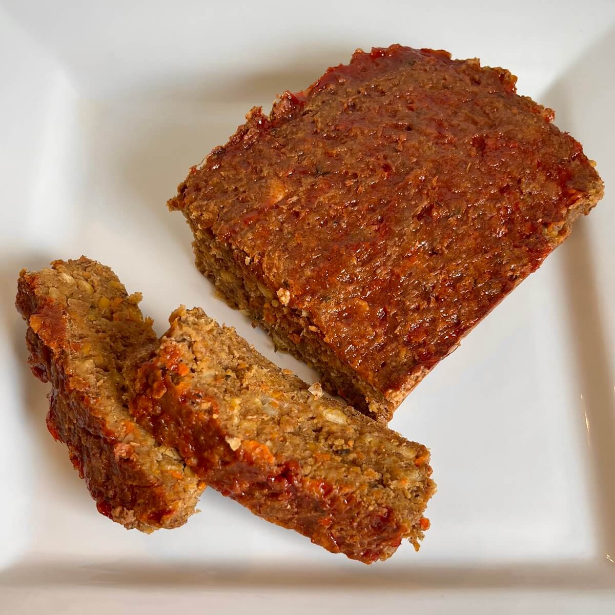 Meatless meatloaf on a plate with two thick slices cut.